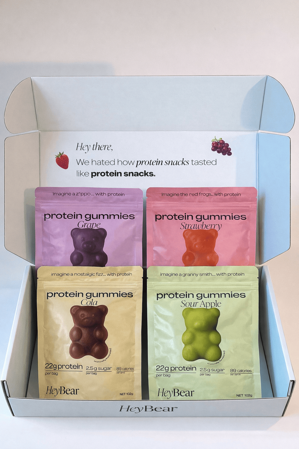 Box of HeyBear protein gummies in various flavors with a light gray background.